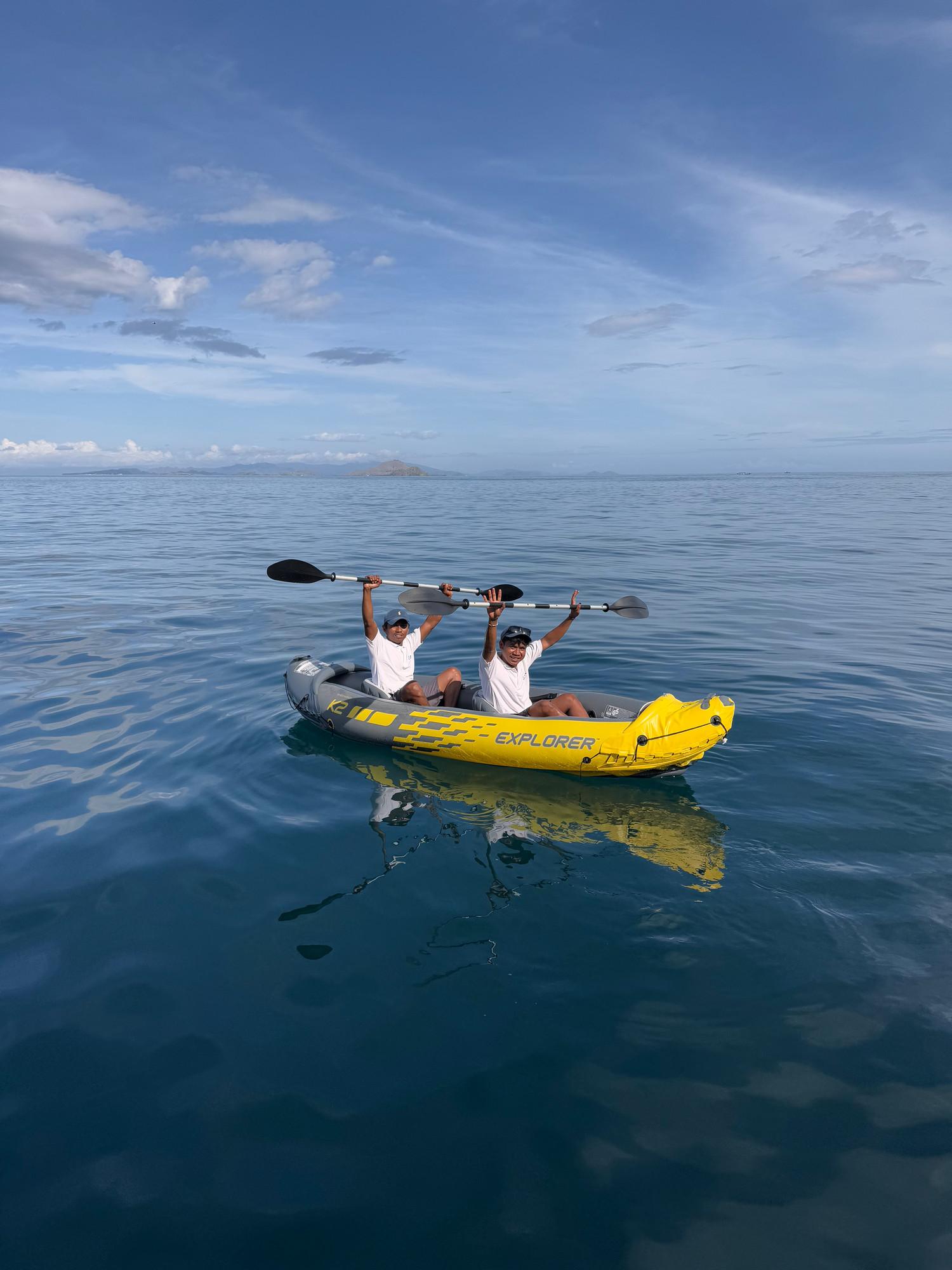 Two people in the inflatable kayak raising their paddles