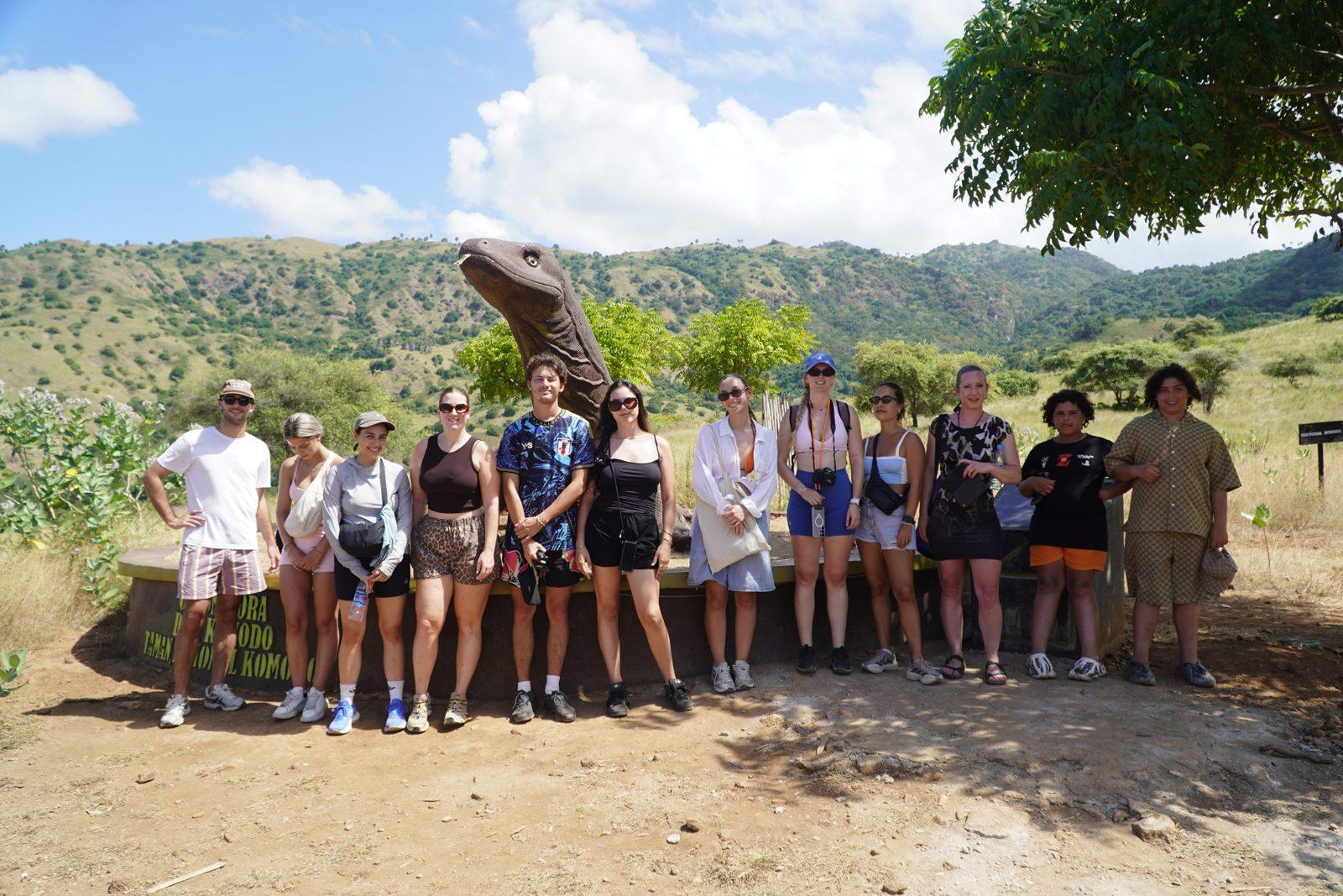 Komodo – group posing on savanna with dragon (Taken on a real Komodo Explorer trip)