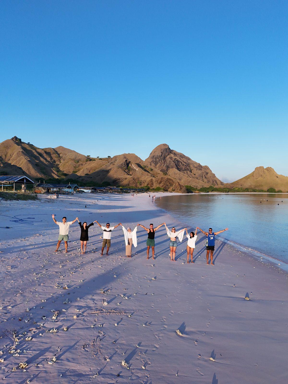 Pink Beach – Group in line on pink sand, hills behind (Taken on a real Komodo Explorer trip)