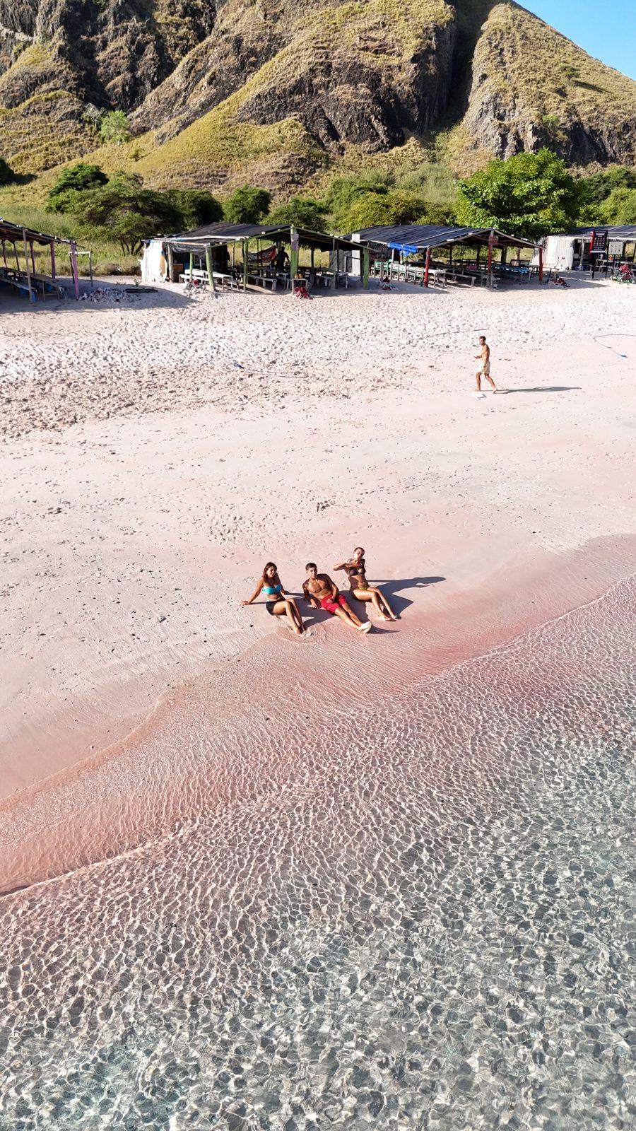 Pink Beach – group lying on pink sand, hill left (Taken on a real Komodo Explorer trip)