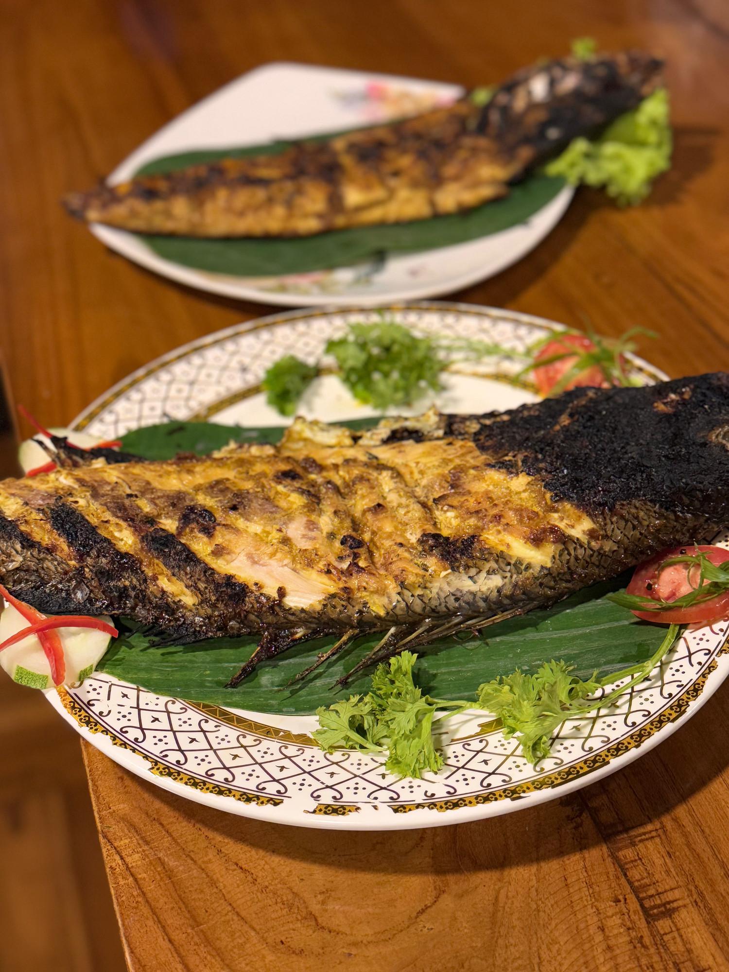 Whole grilled fish on banana leaf with garnish