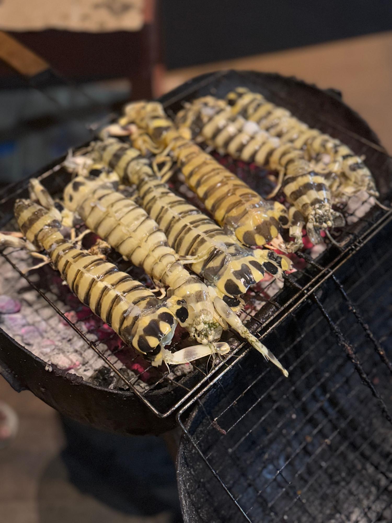 Mantis shrimp grilling over charcoal on deck